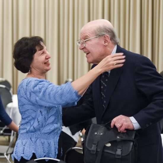 Two emeritus faculty hugging